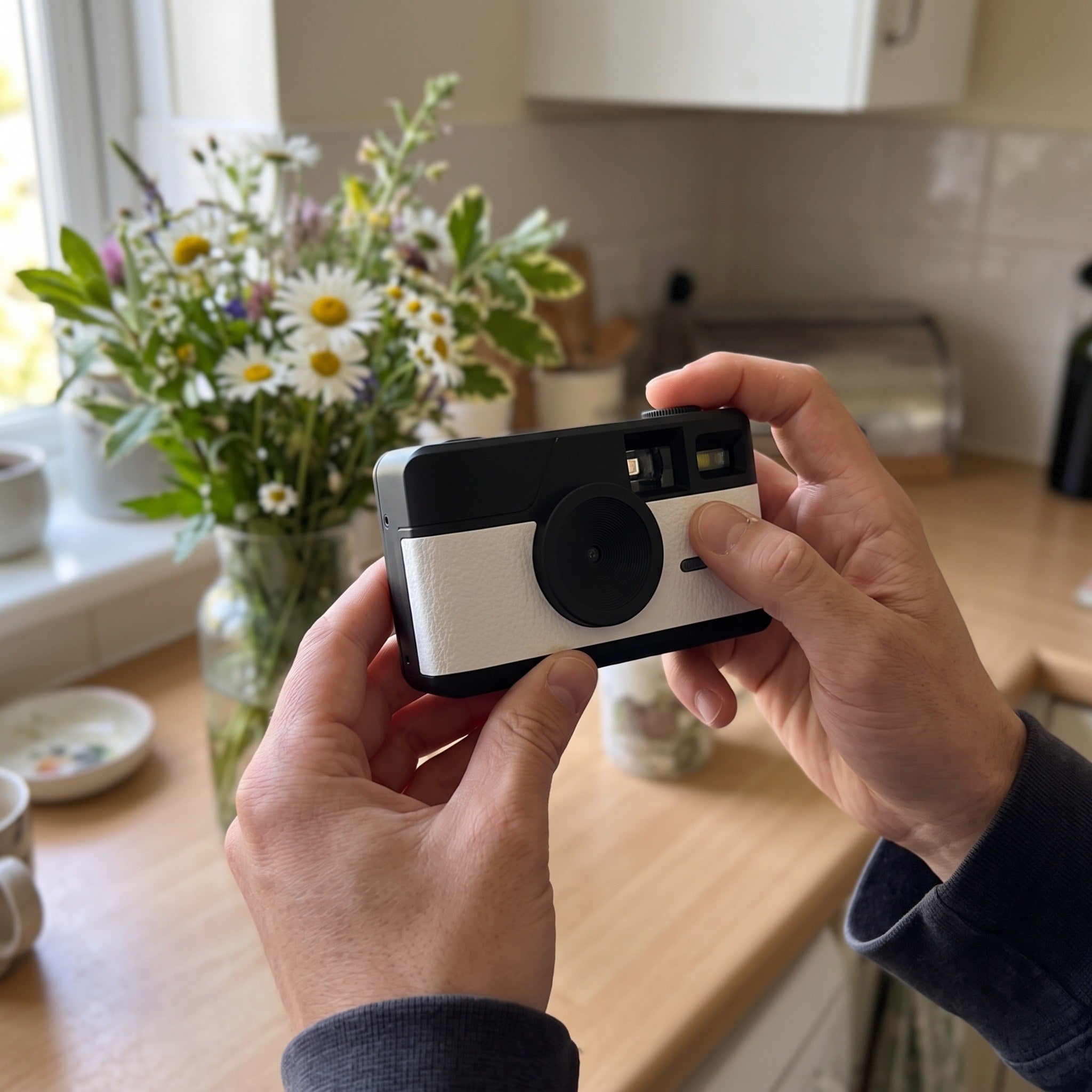White camera framing flowers at a kitchen counter